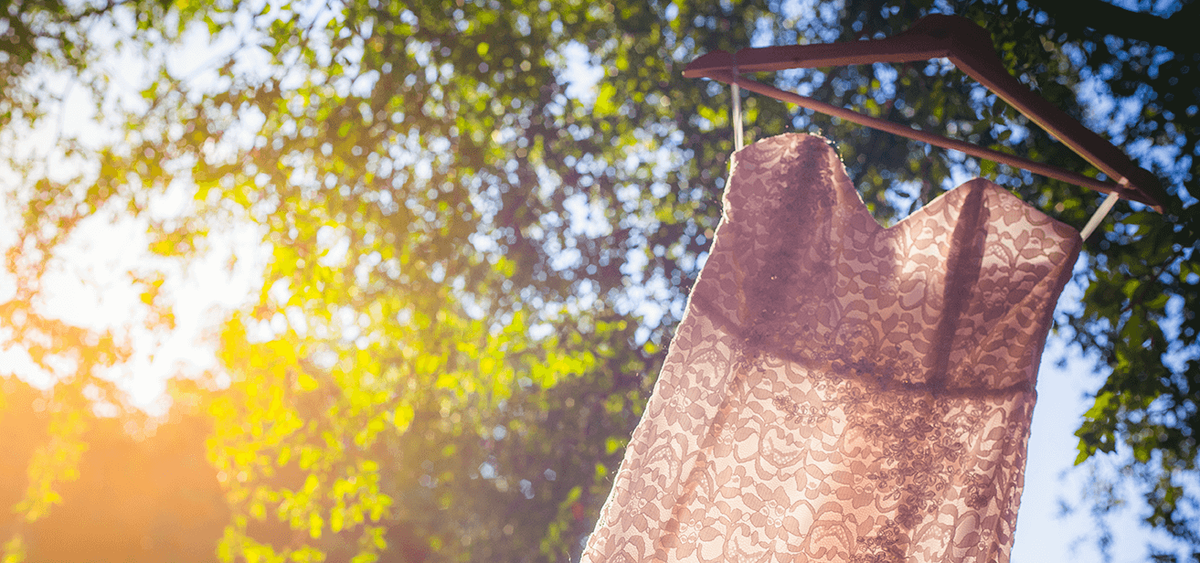 Delicate lace dress hanging outdoors, softly backlit by natural light.