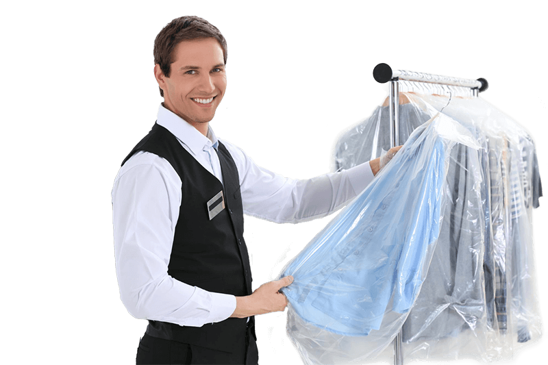 Smartly dressed Cotty’s Cleaners staff member holding a freshly dry-cleaned garment, standing beside a rack of ready-to-pickup clothing.